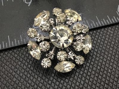 Sale Photo Thumbnail #110: Vintage silver-tone metal starburst brooch featuring multi-tiered clear glass rhinestones in round and marquise cuts. Measures approximately 1.5 inches in diameter. Features a secure rollover safety clasp on the back. Unmarked. In good vintage condition w