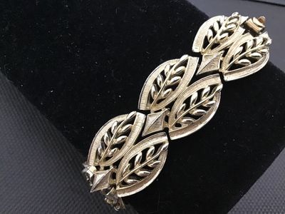 Sale Photo Thumbnail #16: A vintage Coro gold-tone costume jewelry panel link bracelet featuring openwork leaf motif design with textured and polished details. Signed 'Coro' on the fold-over clasp closure. Measures approximately 7 inches in length. In good vintage condition with m