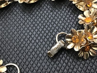 Sale Photo Thumbnail #175: Vintage Coro gold-tone bracelet featuring multi-petal floral links set with amber or topaz-colored rhinestones. Includes a fold-over clasp marked "Coro". Light vintage wear consistent with age, overall good condition with all stones present.