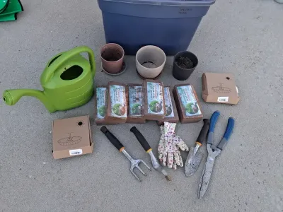 Sale Photo Thumbnail #96: Assorted gardening collection including green plastic watering can, hand trowels, rake tool, shears, floral garden gloves, pots, large storage tote container, coconut coir peat bricks, and boxed solar powered fountain pumps.