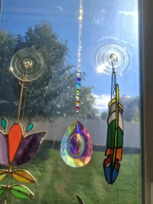 Sale Photo Thumbnail #383: SET OF STAINED GLASS SUN CATCHERS AND CRYSTAL PRISM HANGINGS INCLUDING FLOWER, FEATHER DESIGN, AND MORE. GOOD CONDITION.