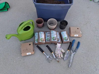 Sale Photo Thumbnail #97: Assorted gardening collection including green plastic watering can, hand trowels, rake tool, shears, floral garden gloves, pots, large storage tote container, coconut coir peat bricks, and boxed solar powered fountain pumps.