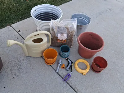 Sale Photo Thumbnail #102: ASSORTED GARDENING SUPPLIES INCLUDING A BAG OF ADAMAN DRIED BSF LARVAE, PLASTIC AND CERAMIC PLANTERS, GALVANIZED BUCKET, WATERING CAN, HOSE NOZZLES, SPRINKLER RING, PRUNERS AND MORE. ITEMS SHOW LIGHT SIGNS OF USE.