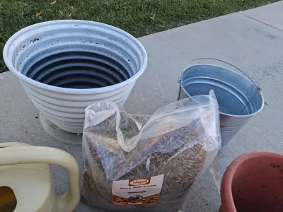 Sale Photo Thumbnail #106: ASSORTED GARDENING SUPPLIES INCLUDING A BAG OF ADAMAN DRIED BSF LARVAE, PLASTIC AND CERAMIC PLANTERS, GALVANIZED BUCKET, WATERING CAN, HOSE NOZZLES, SPRINKLER RING, PRUNERS AND MORE. ITEMS SHOW LIGHT SIGNS OF USE.