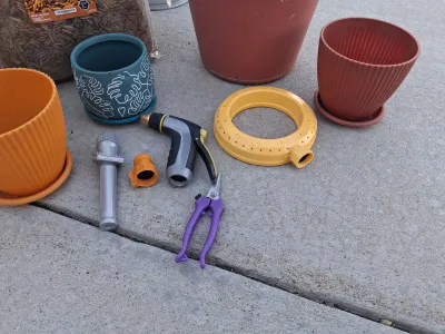 Sale Photo Thumbnail #107: ASSORTED GARDENING SUPPLIES INCLUDING A BAG OF ADAMAN DRIED BSF LARVAE, PLASTIC AND CERAMIC PLANTERS, GALVANIZED BUCKET, WATERING CAN, HOSE NOZZLES, SPRINKLER RING, PRUNERS AND MORE. ITEMS SHOW LIGHT SIGNS OF USE.
