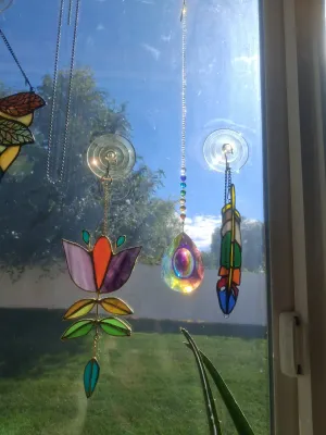 Sale Photo Thumbnail #384: SET OF STAINED GLASS SUN CATCHERS AND CRYSTAL PRISM HANGINGS INCLUDING FLOWER, FEATHER DESIGN, AND MORE. GOOD CONDITION.