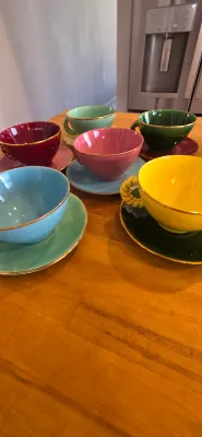 Sale Photo Thumbnail #11: Set of colorful vintage ceramic teacups and saucers featuring gold rims and twisted handles.