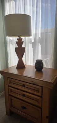 Sale Photo Thumbnail #14: Southwestern-style wooden nightstand featuring three drawers, topped with a geometric carved wood table lamp and a decorative ceramic vessel.
