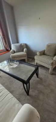 Sale Photo Thumbnail #37: Living room setup featuring a pair of striped upholstered armchairs, matching sofa, and a modern black metal coffee table with a glass top.