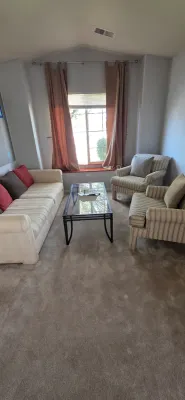 Sale Photo Thumbnail #40: Living room set featuring a cream upholstered sofa, a pair of striped armchairs, and a wrought iron glass-top coffee table.
