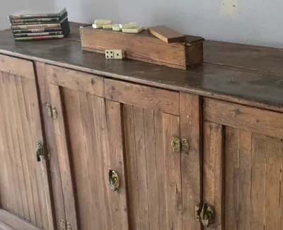 Sale Photo Thumbnail #51: Rustic rustic-style wooden side cabinet or credenza with brass hardware, featuring a wooden domino box and DVDs on top.