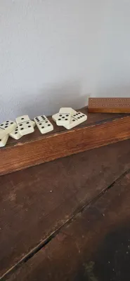 Sale Photo Thumbnail #22: Set of vintage cream-colored dominoes and a wooden cribbage board displayed on a rustic wooden box.