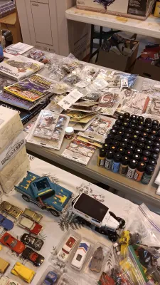 Sale Photo Thumbnail #45: Collection of crafting supplies, small paint bottles, Corvette enthusiast books, and vintage die-cast toy cars displayed on tables.