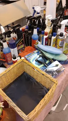 Sale Photo Thumbnail #30: Large assortment of automotive detailing supplies, including spray cleaners, waxes, microfiber towels, and Windshield Wonder tools alongside a woven wicker basket.