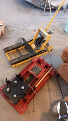 Sale Photo Thumbnail #61: Two hydraulic motorcycle/ATV lifts, including a yellow floor jack and a red platform jack, showing light cosmetic wear from use.