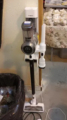Sale Photo Thumbnail #35: Tineco modern cordless stick vacuum cleaner mounted on its wall-style charging dock with attached cleaning accessories.