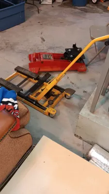 Sale Photo Thumbnail #17: Yellow hydraulic motorcycle and ATV lift jack alongside a red low-profile floor jack on a concrete floor.