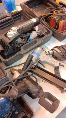 Sale Photo Thumbnail #19: Collection of power tools including a Senco pneumatic nail gun, electric drills, angle grinder with carrying case, and other corded shop equipment.