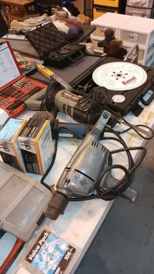 Sale Photo Thumbnail #16: Collection of power tools and shop supplies including a vintage heavy-duty electric drill, Porter-Cable reciprocating saw, angle grinder, and precision timing equipment in hard cases.