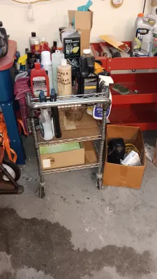 Sale Photo Thumbnail #7: Three-tiered metal rolling wire cart filled with various automotive detailing supplies, cleaners, and waxes.