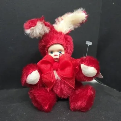 Plush rabbit doll featuring a porcelain face and a red fluffy suit with a large bow.