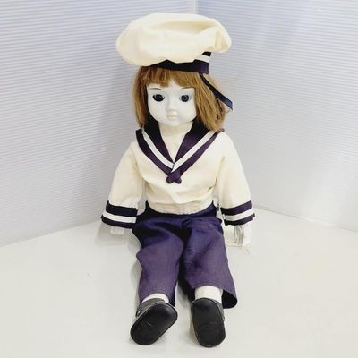 Porcelain doll dressed in a navy and white sailor outfit with matching hat and shoes.