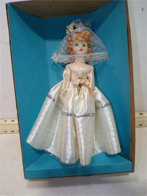 Vintage bridal fashion doll in original packaging, dressed in a white satin gown with lace trim, floral waist accents, and a netted veil.