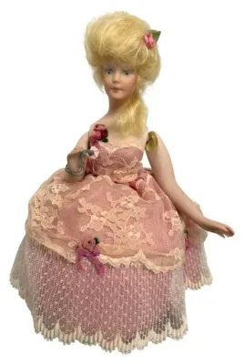 Vintage half-doll or boudoir doll featuring blonde hair in a high updo, wearing an elaborate pink and cream lace dress adorned with...