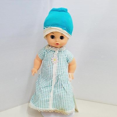 Vintage baby doll wearing a light blue and white checkered dress with lace trim and a blue bonnet.