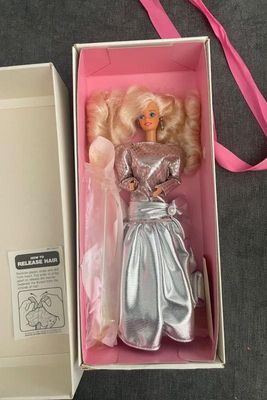 Vintage 1980s Barbie doll in original pink inner packaging box, featuring big blonde hair and a metallic silver gown with pearl accent.