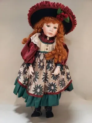 Victorian-style collector doll featuring curly red hair, a ornate ruffled bonnet, and a multi-layered floral and lace dress.