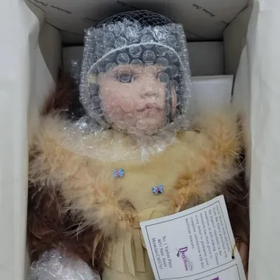 Duck House porcelain collector doll in original box, featuring a Native American style outfit with faux fur trim, protectively wrapped in...