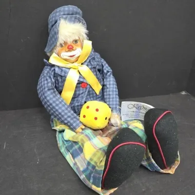 Vintage Kasma Collection porcelain clown doll dressed in blue checkered and plaid attire, holding a yellow plush die.
