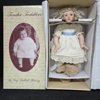 Gay Talbott Boassy "Tender Toddlers" collectible porcelain doll with curly blonde hair, wearing an ivory dress with blue sash,...