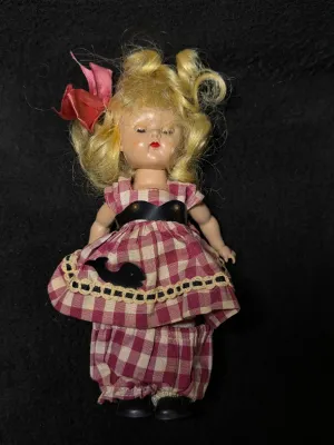 Vintage hard plastic storybook doll with blonde hair, wearing a red and white gingham dress with matching bloomers and a pink hair bow,...