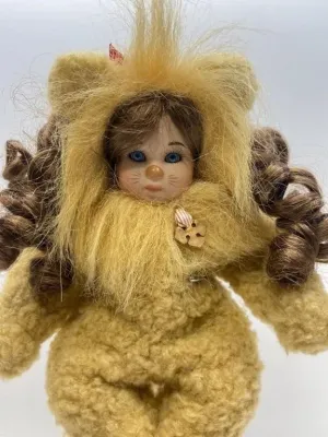 Collectible porcelain doll dressed in a fuzzy lion costume inspired by The Wizard of Oz, featuring curly brown hair and painted facial...