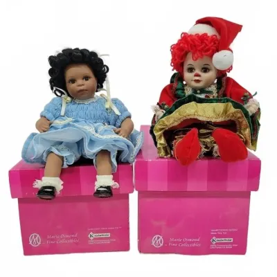 Two Marie Osmond Fine Collectibles porcelain dolls sitting on their original pink boxes, including one in a blue smocked dress and one...