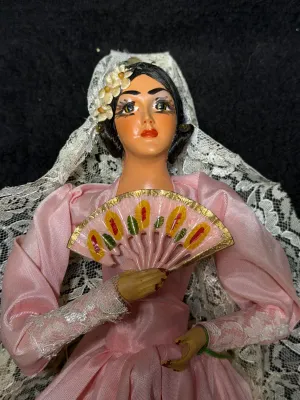 Vintage souvenir Flamenco doll dressed in a pink satin gown with a white lace mantilla and hand fan.