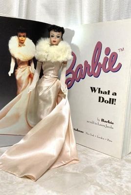 Vintage Barbie doll dressed in the 'Enchanted Evening' satin gown and faux fur stole, posed in front of the coffee table book...