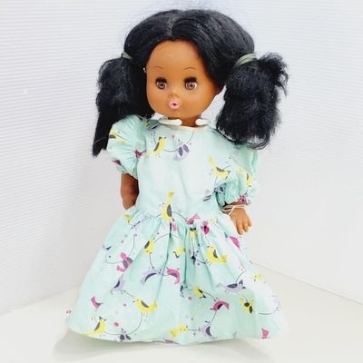 Vintage Black baby doll with black pigtails, dressed in a light blue floral and bird print dress.