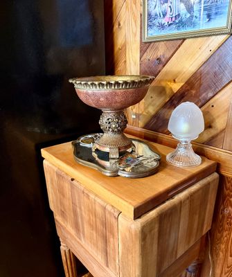 Ornate crackle-glazed pedestal bowl displayed on a mirrored tray alongside a small frosted glass lamp, sitting atop a wooden drop-leaf...