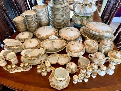 Extensive vintage fine china dinnerware service featuring elaborate gold filigree scrollwork and trim, including stacks of plates,...