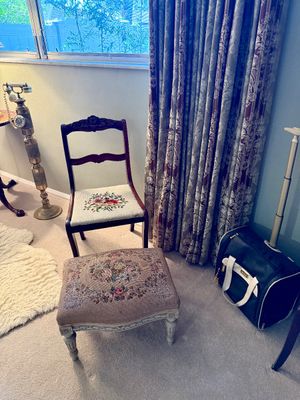 Vintage side chair and matching ottoman featuring floral needlepoint upholstery, paired with a brass candlestick-style telephone lamp.