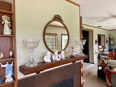 Vintage round wall mirror with an ornate gold-tone frame, mounted above a mantle displayed with cut crystal pedestals, white cherub...