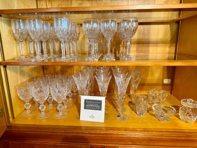 Large collection of Waterford cut crystal stemware and tableware displayed in a wooden hutch, featuring pieces from The Millennium...