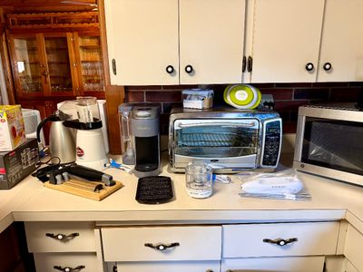 Collection of modern kitchen appliances, including an Oster toaster oven, a Keurig single-serve coffee maker, a GE microwave, an electric...