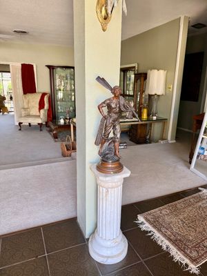 French style bronze figure of a fisherman holding nets and an oar, displayed atop a carved white marble pedestal column.