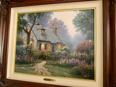 Framed Thomas Kinkade canvas print depicting a cozy stone cottage surrounded by a lush garden, set in an ornate carved wood frame with a...