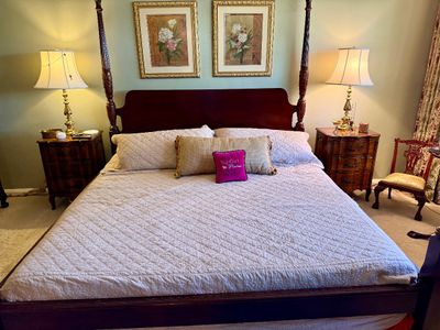 Traditional dark wood four-poster king bed set, complemented by matching three-drawer nightstands and brass table lamps.