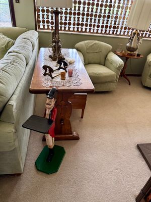 Living room scene featuring a painted wooden butler drink stand, a traditional trestle sofa table, and green upholstered seating.
